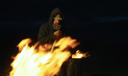 A man standing in front of a fire