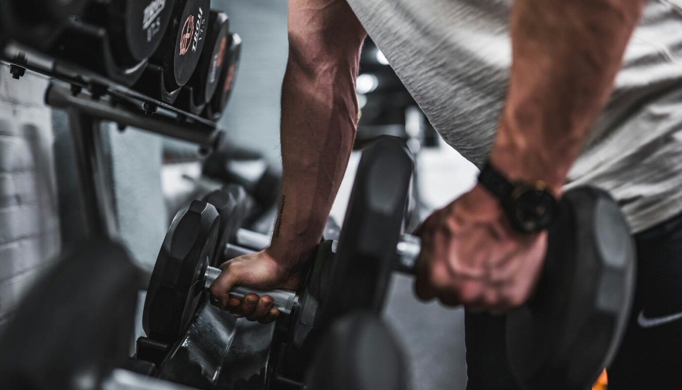 person in gray shirt holding black dumbbell