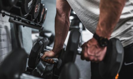 person in gray shirt holding black dumbbell