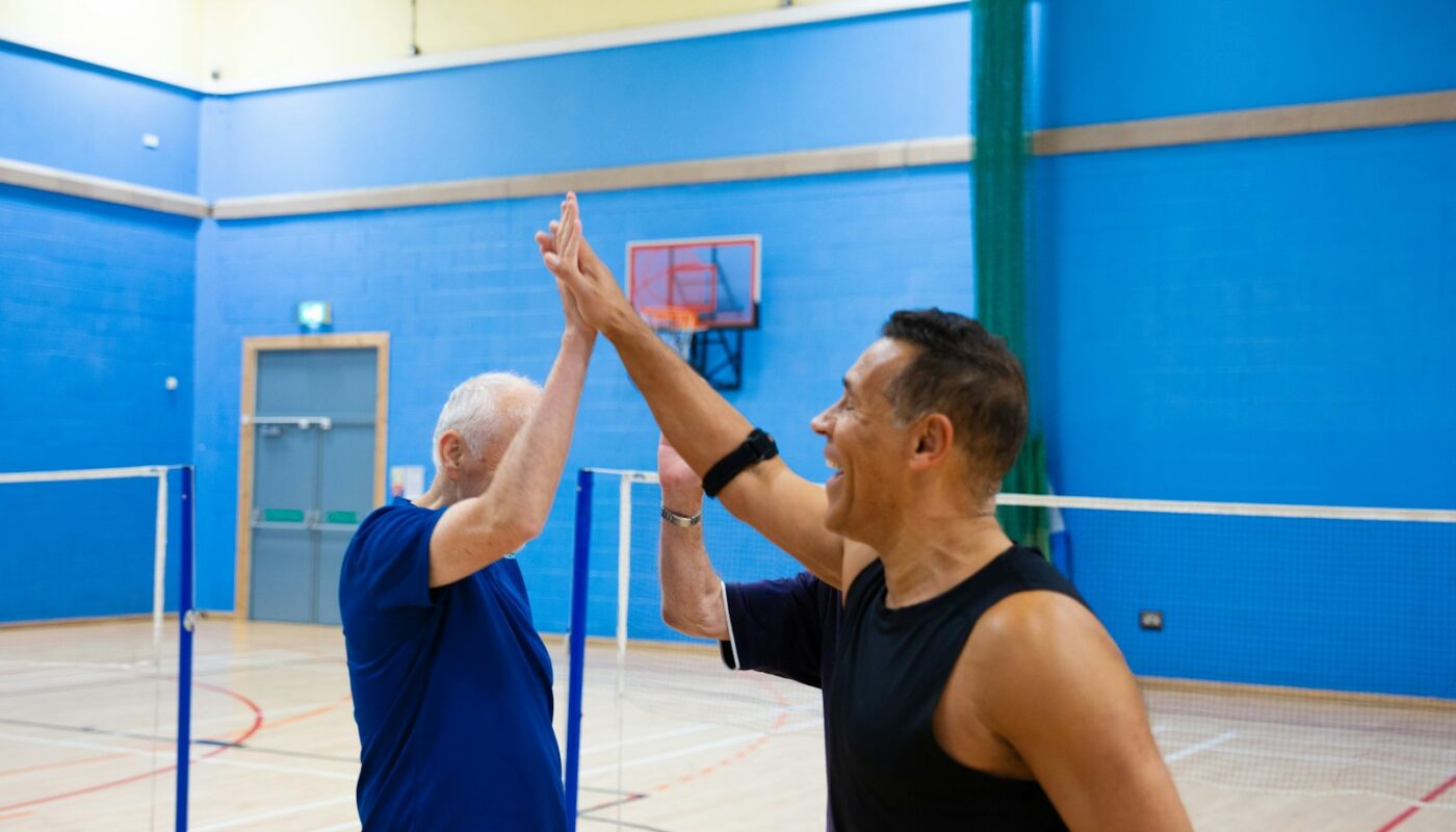 Two men giving each other a high five indoors.