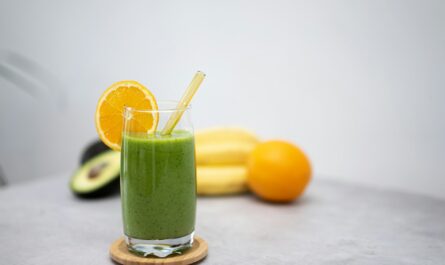 a green smoothie with an orange slice and a straw