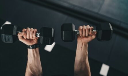 a man lifting two dumbs in a gym